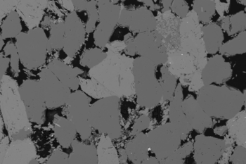 Raster-Elektronen-Mikroskop-Bild von einem Sandstein. Im Schwarz sind die Porenräume gezeigt. A scanning electron microscope image of sandstone. The pore space is shown in black.