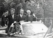John F. Kennedy kommt an – im offenen Wagen mit Konrad Adenauer und Willi Brandt.