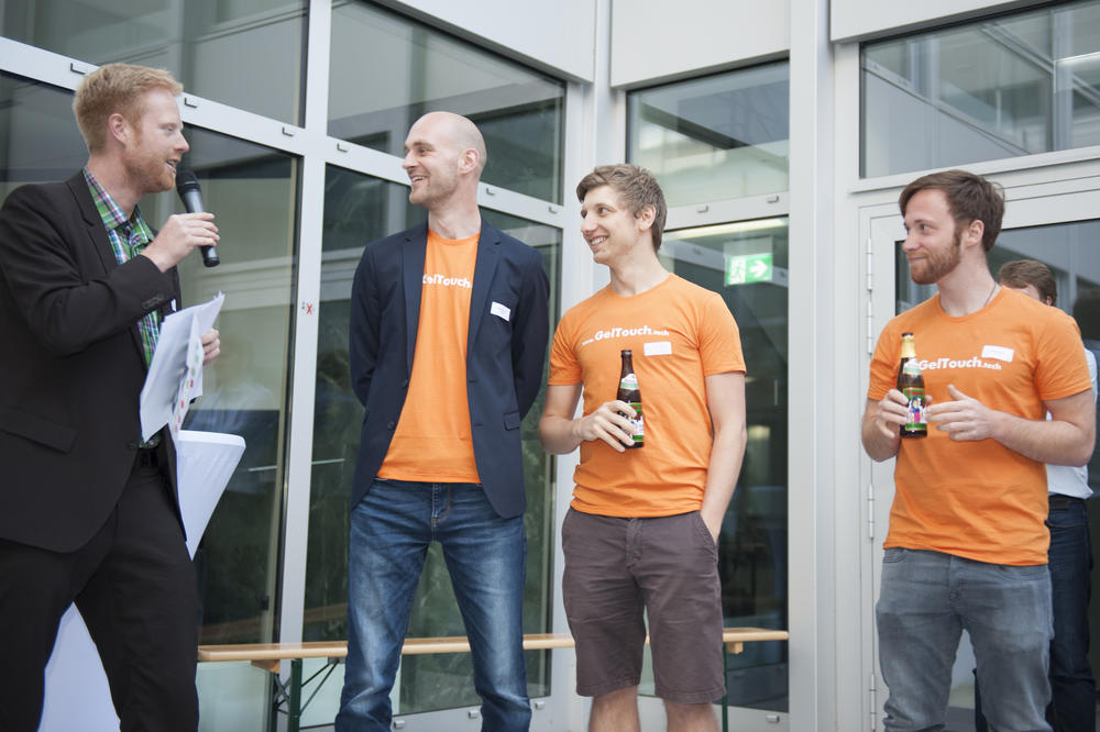 Auftakt zum geselligen Teil des Abends: Das Team GelTouch Technologies (v. r. n. l.: René Sachse, Paul Krause und Christian Stöcklein) wird von Steffen Terberl (l.), Leiter von Profund, für den besten Pitch ausgezeichnet.