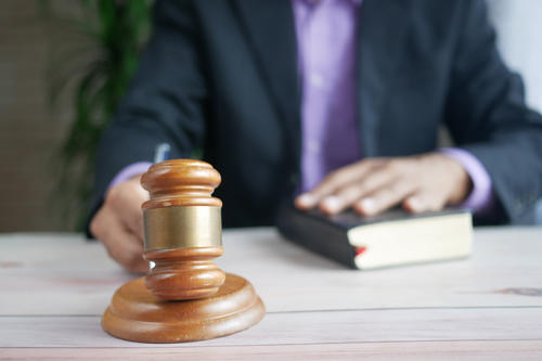 Person im Anzug mit Richterhammer aus Holz