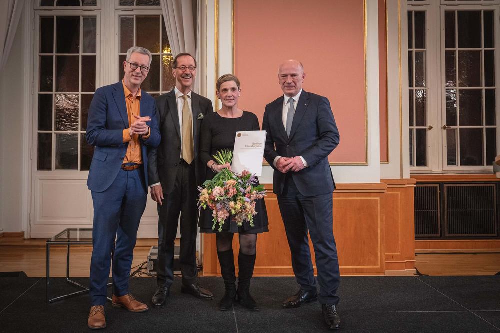 Gruppenfoto mit Blumenstrauß und Urkunde (v. l.): Universitätspräsident Professor Günter M. Ziegler, Stiftungsvorsitzender Hans Gerhard Hannesen, Preisträgerin Felicitas Hoppe, Bürgermeister Kai Wegner.