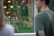 Lea Ebeling vom Kollektiv Orange bemalte die Fensterscheiben der Mensa II mit Illustrationen zur Lebensweise verschiedener Wildbienenarten auf dem Campus – Kunstwerk und Vogelschlagschutz zugleich.
