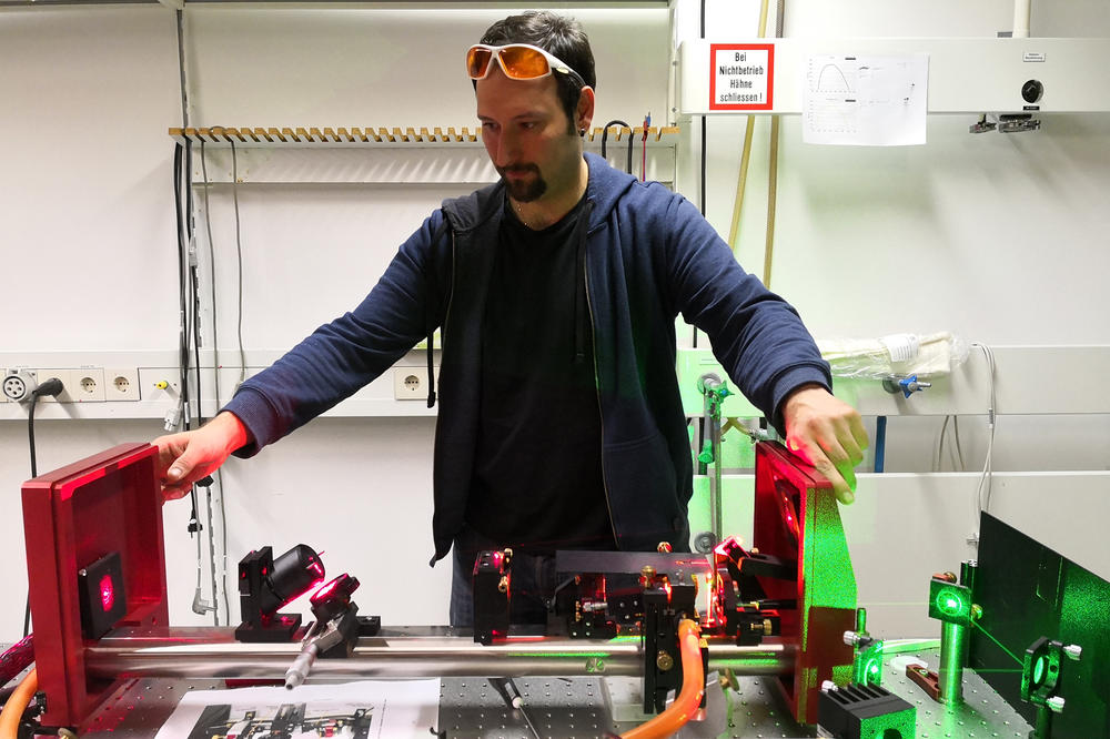 Postdoktorand Patryk Kusch – hier vor dem Messlaser der Freien Universität – recherchierte mit dem Forscher-Alumni-Stipendium an der Universidade Federal de Minas Gerais in Brasilien.