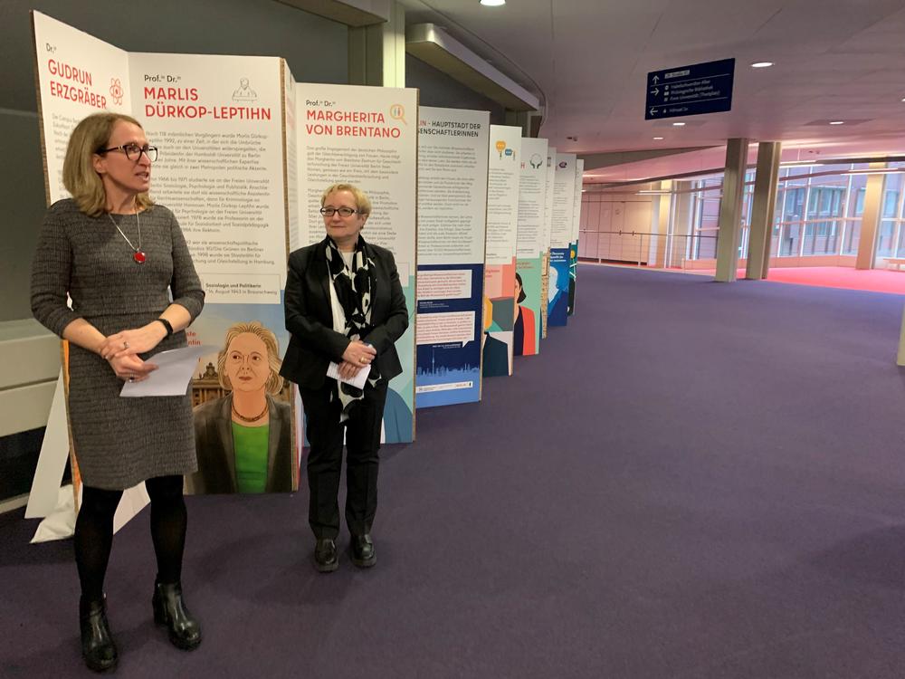 Heike Pantelmann (l.) und Verena Blechinger-Talcott (r.) eröffneten vor Beginn der Podiumsdiskussion die Ausstellung „Hauptstadt der Wissenschaftlerinnen“ im Garderobenfoyer der Rostlaube. Die Ausstellung ist noch bis zum 7. März zu sehen.