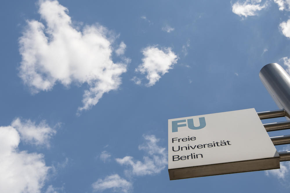 Der Himmel über Dahlem. Darunter ein Wegweiser zum Campus der Freien Universität Berlin.