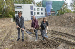 Spatenstich in lehmigem Boden: Kanzlerin Dr. Andrea Bör (M.), Romanistikprofessorin Dr. Anita Traninger (r.), Sprecherin des Exzellenzclusters Temporal Communities, und Architekt Tiemo Klumpp.