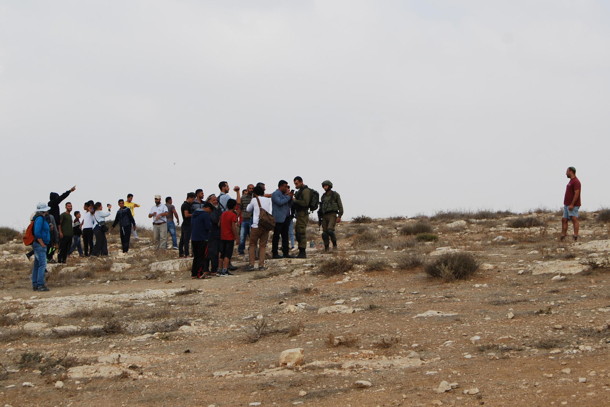 Am Hill 833: Ein Siedler steht einer Gruppe von Palästinensern gegenüber. Er lässt seine Pistole, die er in seiner rechten Hosentasche hat, keinen Moment los. Palästinenser filmen, um sich zu schützen. Israel Defense Forces versuchen zu vermitteln.