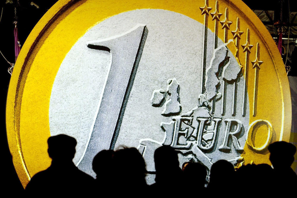 A giant euro coin towers over a crowd in Frankfurt city center on the morning of December 17, 2001. This was where the first coin bags with a selection of the new euro coins were sold.