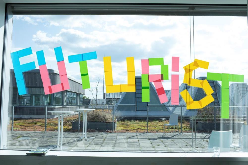 Blau leuchtender Schriftzug ‚FUTURIST‘ auf einer dunklen Fensterscheibe, im digitalen, futuristischen Stil gestaltet.