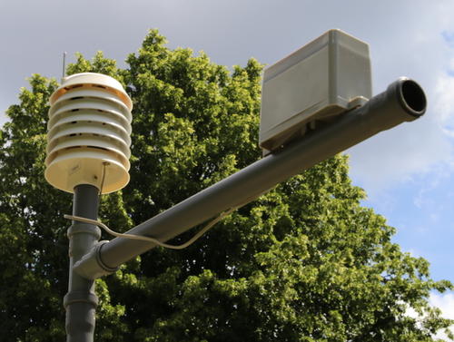 Messgerät aus passiv belüftetem Gerät mit Sensoren für Temperatur, Feuchte, Druck, Strahlung sowie Solarzellen und Akku (links), Niederschlagsmesser (rechts).