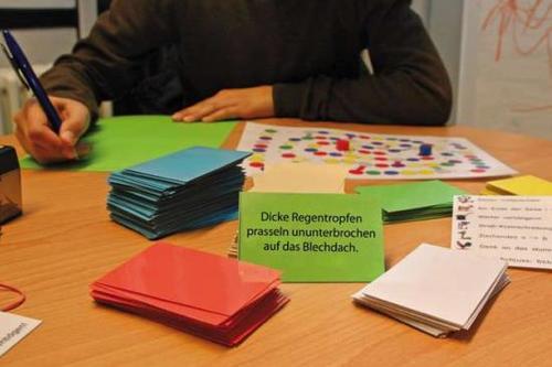 Sätze wie „Dicke Regentropfen prasseln ununterbrochen auf das Blechdach“ können mithilfe von Spielkarten leichter erlernt werden.