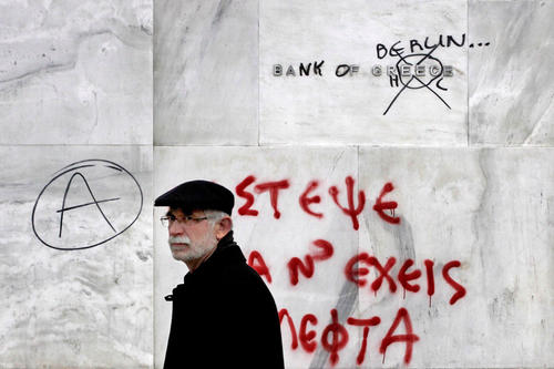 „Raube, um Geld zu haben“ steht in roter Farbe und griechischer Schrift an der Mauer der Bank von Griechenland in Athen, deren währungspolitische Rolle 2001 mit der Einführung des Euro die Europäische Zentralbank übernahm.