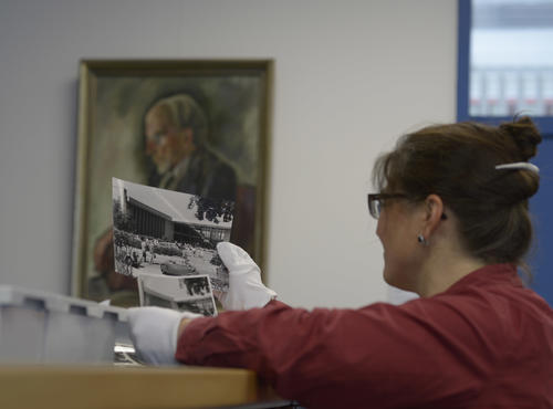 Mit Schutzhandschuhen sieht Birgit Rehse, die Leiterin des Archichs, alte Fotografien vom Henry-Ford-Bau der Freien Universität durch.