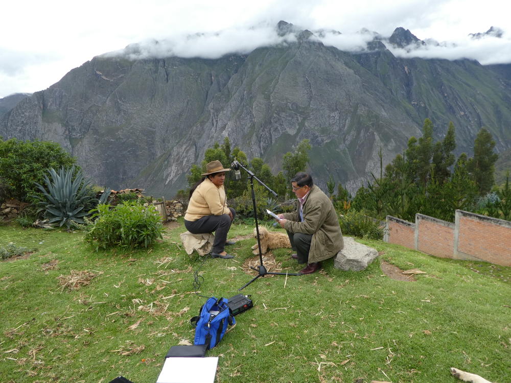 Projektmitarbeiter Gabriel Barreto (rechts) und eine einsprachige Sprecherin des Quechua sitzen vor einem Bergpanorama und machen Sprachaufnahmen.