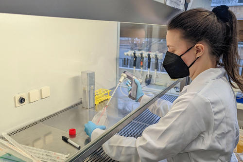 Biochemikerin mit Kittel und Maske arbeitet im Labor