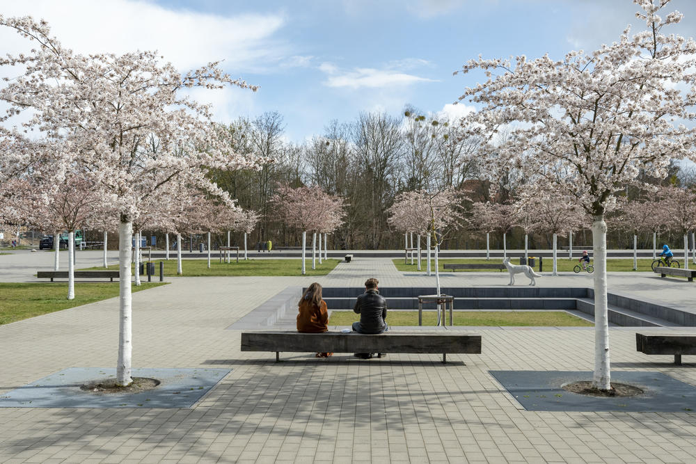 Zwei Personen sitzen auf einer Bank auf dem Platz vor der Silberlaube.